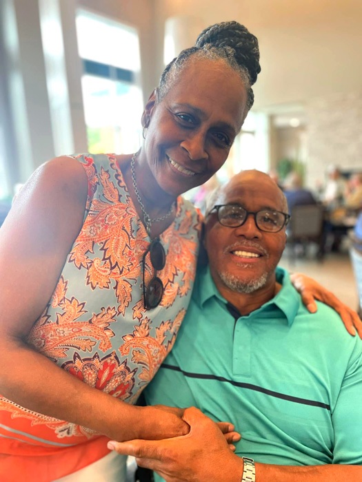 Smiling couple sharing a warm embrace in a bright, lively community space, highlighting love, companionship, and the joy of spending quality time together.