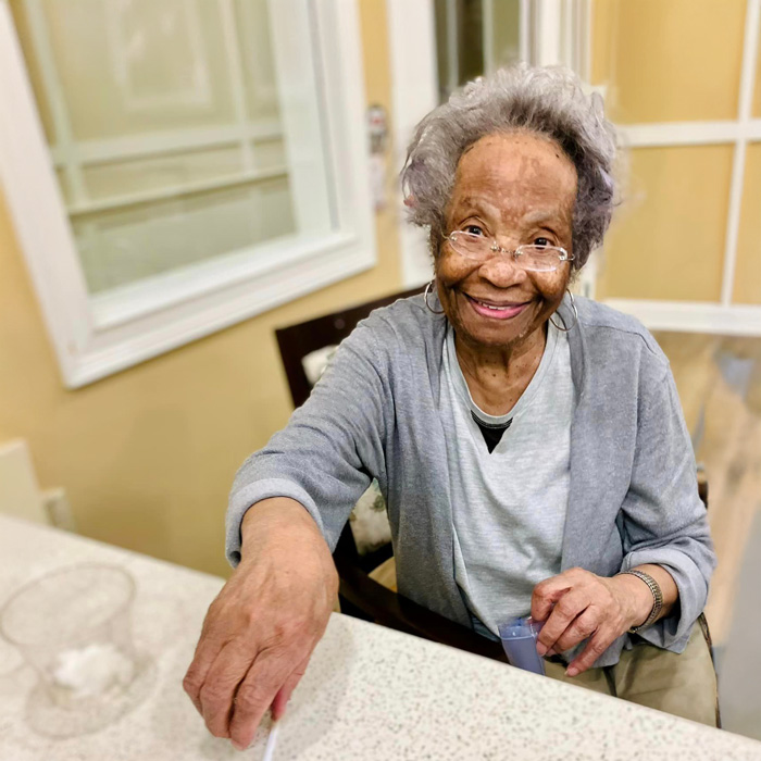 Senior resident smiling while participating in a pop-up happy hour event, happily reaching for a snack or drink, embodying the joy of community engagement in senior living.
